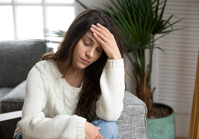 Frau fasst sich an den Kopf Magnesiummangel bringt Kopfschmerzen